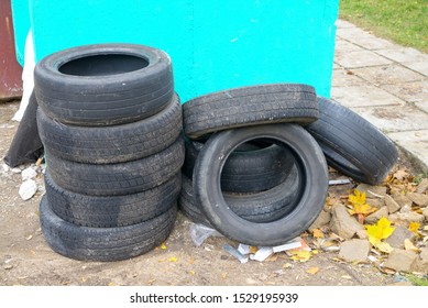 A Stack Of Old Used Rubbish Tires From The Vehicle Lies Near The Light Green Wall Of The Trash. Concept Of Recyclables For Further Processing Or Buying New Tires Instead Of Old Ones.