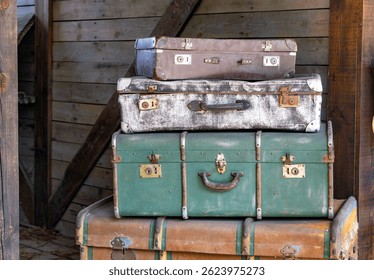 stack of old, weathered suitcases and trunks arranged in a rustic wooden setting. Each piece shows signs of age and use, giving the scene a strong vintage and nostalgic feel. Perfect for themes relate