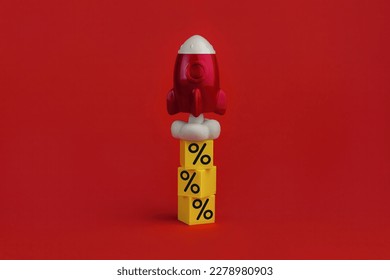 stack on yellow cubes with percent signs and flying up rocketship on red background. Concept of buying and increasing cashback
