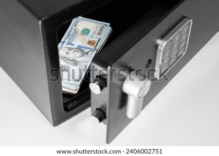 Stack of one hundred dollar bills banknotes in an open black digital steel safe box on a white isolated background