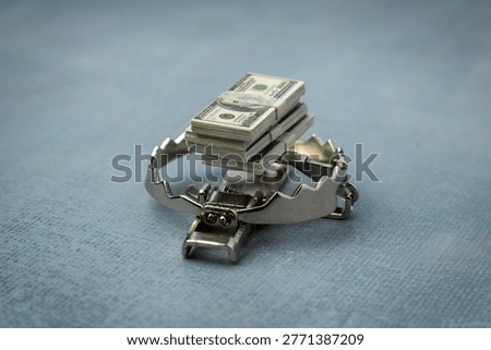 A stack of one hundred dollar bills used as bait on a steel trap. Financial greed, debt traps, money scams, and high-risk investments concept.