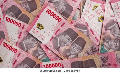 Stack of One Hundred Thousand Rupiah Banknotes in red or pink. Close-up shot of one hundred thousand rupiah banknotes. Indonesian Currency