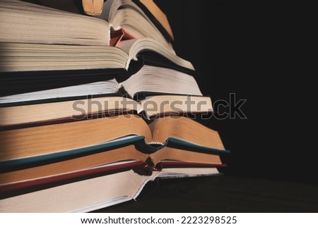 a stack of open books in the dark. The open books are stacked on top of each other. Books in a dark room in a vintage style. lots of books on a dark background.