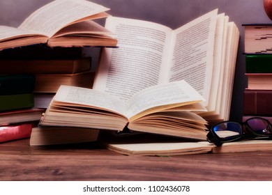Stack of open books on the table in the background of a school blackboard. Back to school.