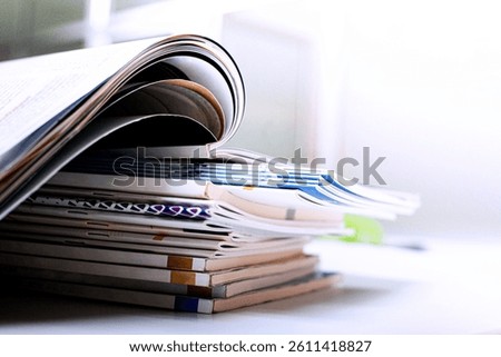Stack of open magazines on white background, shallow depth of field.
