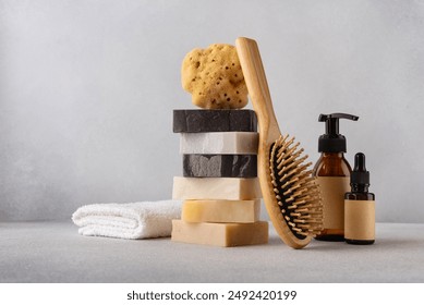 Stack of organic soap bars, bamboo hair comb, cosmetic bottles, natural sponge and cotton towel. Bathroom and wellness concept.