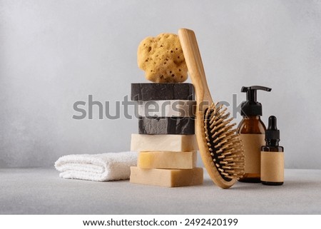 Stack of organic soap bars, bamboo hair comb, cosmetic bottles, natural sponge and cotton towel. Bathroom and wellness concept.