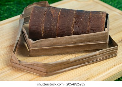 A stack of the palm sugar with dried coconut leaves used for packing. Selective focus points. Blurred background