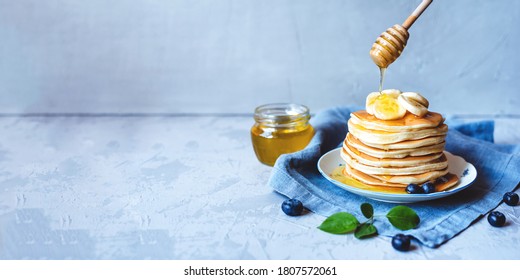 A stack of pancakes with fresh banana, blueberry and honey. Delicious homemade breakfast. Banner with copy space for text. - Powered by Shutterstock