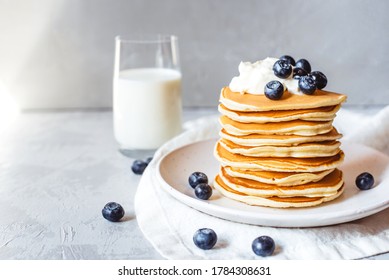 A stack of pancakes with fresh blueberries, cheese cream and glass of milk. Delicious homemade breakfast. - Powered by Shutterstock