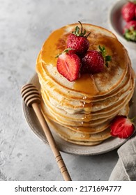 Stack Of Pancakes With Honey, Strawberries And Honey Spoon On Gray Background Close Up. Vertical Orientation