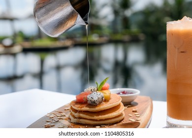 Stack Of Pancakes With Honey Syrup At Pool Side And Glass Of Ice Tea