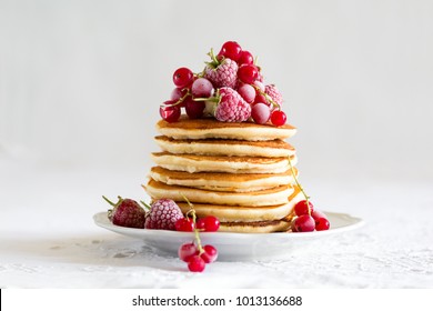 Stack of pancakes with raspberry, red currant, cream and honey on white table cloth - Powered by Shutterstock