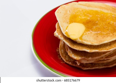 stack of pancakes served on a red plate with butter melting on top