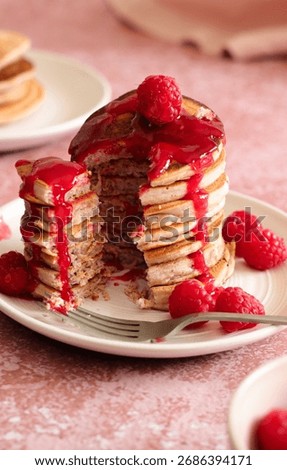 Stack of pancakes sliced open and dripping with rasberry sauce