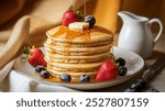 Stack of pancakes with syrup, butter, strawberries, and blueberries