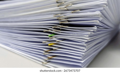 Stack of paper documents with metal and colored paper clips. Close-up of office paperwork, reports, files, and corporate organization.