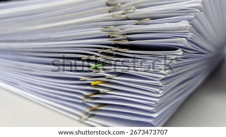Stack of paper documents with metal and colored paper clips. Close-up of office paperwork, reports, files, and corporate organization.