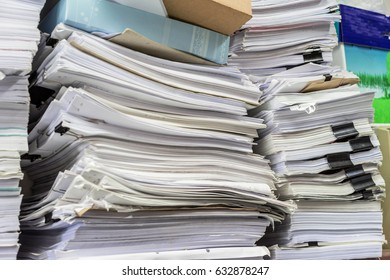 The stack of paper lay on a messy table in the office in the storage room.