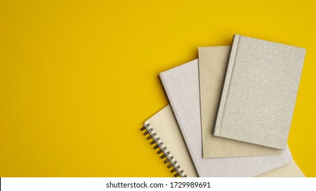 Stack of paper notebooks on yellow background. Flat lay, top view school of office supplies. - Powered by Shutterstock