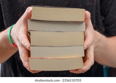 A stack of paperback books held in hands