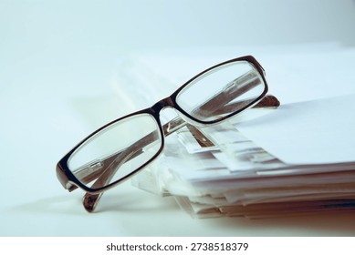 Stack of papers and eyeglasses on white background, business concept