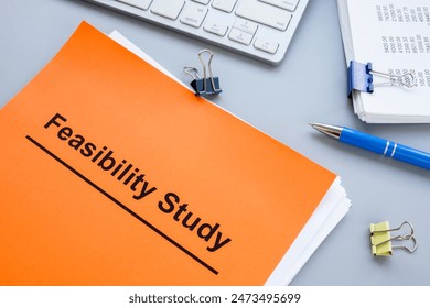 Stack of papers with feasibility study and keyboard.