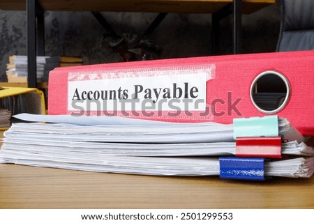 Stack of papers and folder labeled accounts payable. Financial management and accounting tasks.