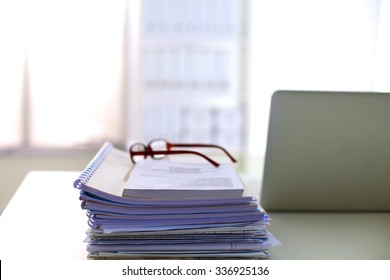 Stack of papers and glasses lying on table desaturated