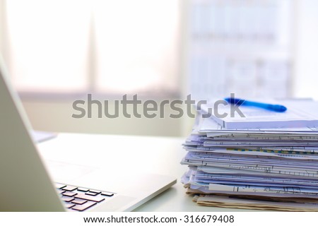 Stack of papers and glasses lying on table desaturated