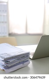 a stack of papers on the desk with a computer