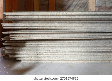 Stack of particleboard sheets in an indoor setting