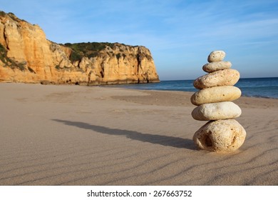 stack of pebble on sandy beach with cliff in the background