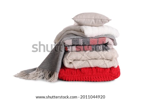 Stack of pillows and folded warm plaids on white background