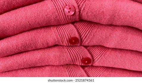 A stack of pink woolen cardigans. Sweaters.Cozy autumn and winter wardrobe, warm knitted clothes,close-up, retail clothing background.Selective focus.