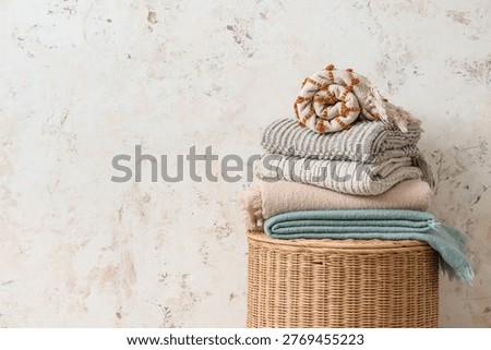 Stack of plaids on basket near light grunge wall