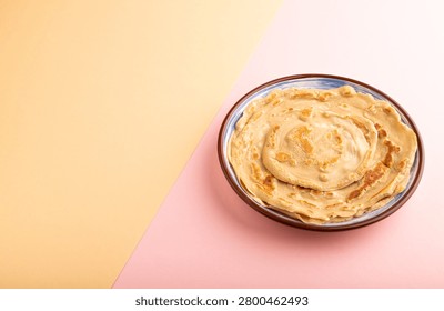 Stack of Plain Fried pancakes on pink and orange pastel paper background. side view, copy space
