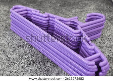 Stack of Plastic Clothes Hangers with Trouser Bar and Shoulder Notches Hangers for Clothes Good Quality Plastic Hangers with purple color.