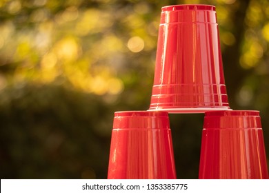 A Stack Of Plastic Red Solo Drinking Cups For Beer Pong Or Drinking Games With Green Background On A White Table. 