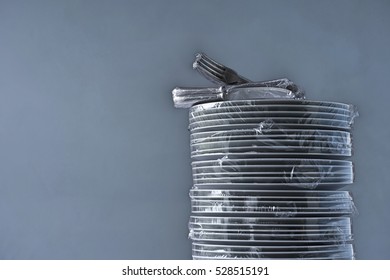 Stack of plates and cutlery wrapped in plastic