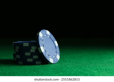 Stack of poker chips on green table against dark background, closeup. Space for text