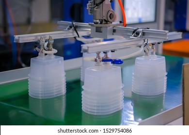 Stack of polypropylene food containers on conveyor belt of automatic plastic injection molding machine with robotic arm at exhibition, trade show. Manufacturing, industry, automated technology concept
