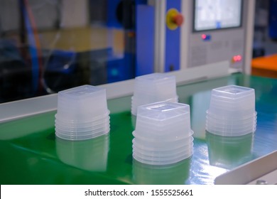 Stack Of Polypropylene Food Containers On Conveyor Belt Of Automatic Plastic Injection Molding Machine At Fabric, Exhibition, Trade Show. Manufacturing, Industry, Automated Technology Concept