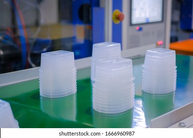 Stack Of Polypropylene Food Containers On Conveyor Belt Of Automatic Plastic Injection Molding Machine At Fabric, Exhibition, Trade Show. Manufacturing, Industry, Automated Technology Concept