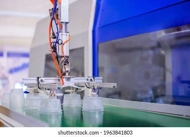 Stack Of Polypropylene Food Containers On Conveyor Belt Of Automatic Plastic Injection Molding Machine With Robotic Arm At Exhibition, Trade Show. Manufacturing, Industry, Automated Technology Concept