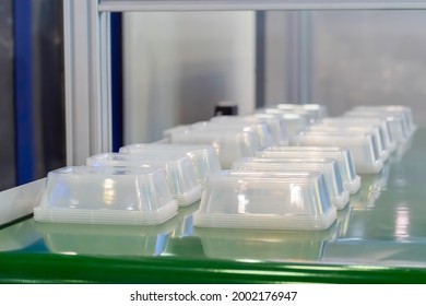 Stack Of Polypropylene Food Containers On Conveyor Belt Of Automatic Plastic Injection Molding Machine At Exhibition, Factory. Industry, Manufacturing, Automated Technology Concept