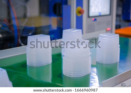 Stack of polypropylene food containers on conveyor belt of automatic plastic injection molding machine at fabric, exhibition, trade show. Manufacturing, industry, automated technology concept Stock photo © 