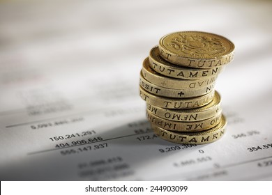 Stack of pound coins on financial figures balance sheet