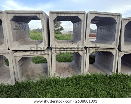 A stack of precast box culverts on a plot of land by the roadside