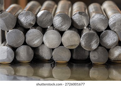 Stack of precious metal rods lying on an oil-covered metal surface with visible circular cross sections in industrial lighting. Concept of metallurgy, manufacturing, raw materials, heavy industry and metal processing.